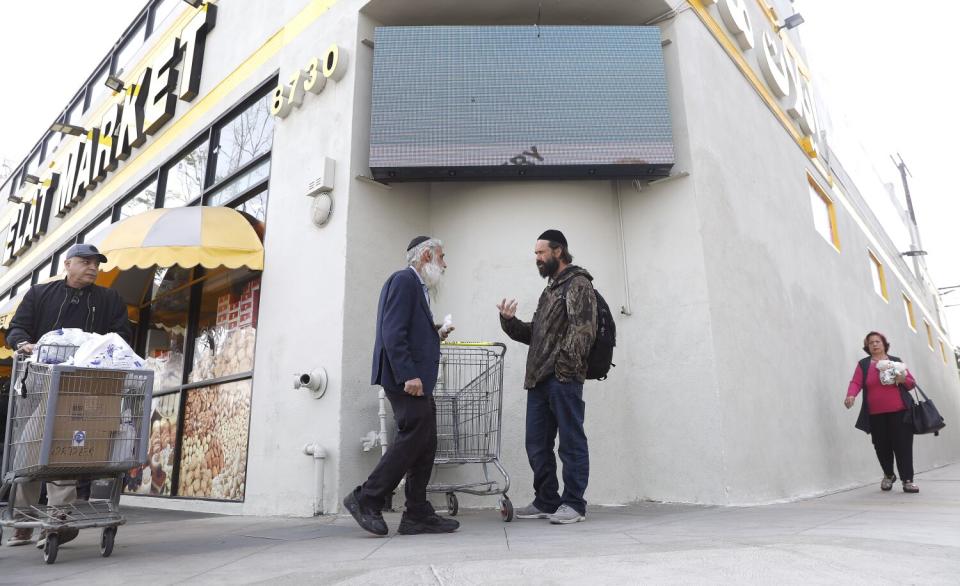 People pass by Elat Market along Pico Boulevard.