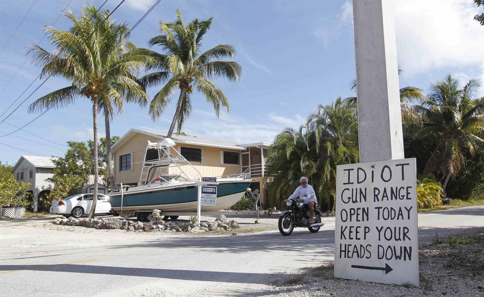 A sign placed by a neighbor is seen at the intersection closest to the home of Doug Varrieur in Big Pine Key in the Florida Keys March 5, 2014. Varrieur, 57, discovered a little-noticed part of Florida law which prohibits local governments from restricting gun rights in any way, and in December he set up a personal gun range on his property in a residential subdivision. Neighbors were outraged by the live gunfire, but their surprise was nothing compared to that of municipal leaders, who were shocked to realize there was nothing they could do about it. Picture taken March 5, 2014. REUTERS/Andrew Innerarity (UNITED STATES - Tags: SOCIETY)