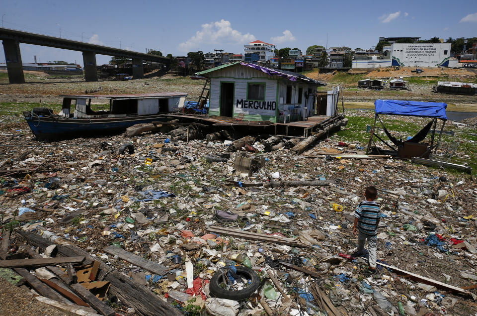 FILE 0 Boys walk next to a floating home stranded on what used to be the water's edge of the Negro River, amidst a drought in Manaus, Brazil, Sept. 26, 2023. The extreme drought sweeping across Brazil’s Amazon rainforest is already impacting hundreds of thousands of people and killing local wildlife. (AP Photo/Edmar Barros, File)