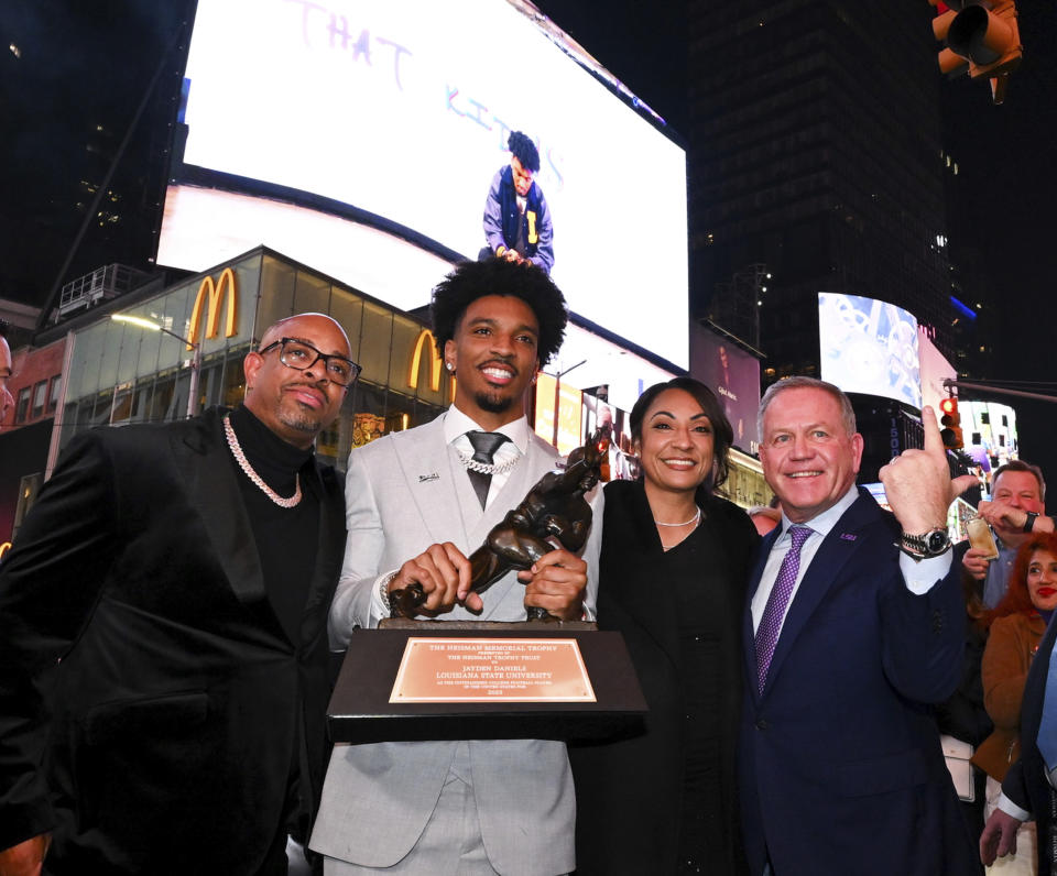 Jayden Daniels holds the Heisman Trophy with standing in Times Square with family and LSU coach Brian Kelly, right, Saturday, Dec. 9, 2023, in New York. (Todd Van Emst/Pool Photo via AP)