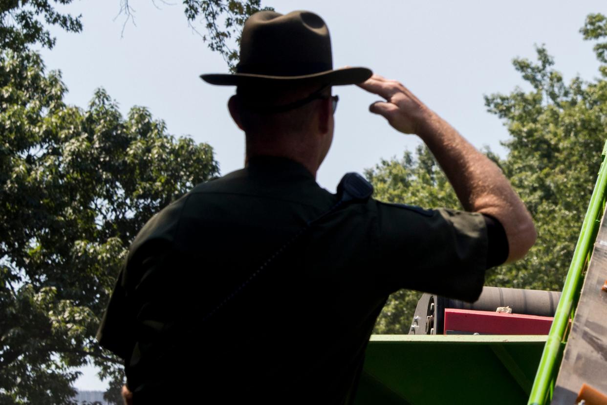 A New York State Environmental Conservation officer salutes as an ivory sculpture rolls up a conveyor belt into a crusher, Thursday, Aug. 3, 2017