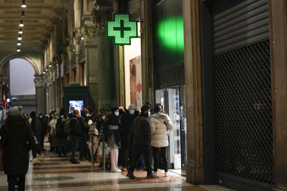 People line up outside a pharmacy for COVID-19 swab tests, in Milan, Italy, Thursday, Dec. 23, 2021. The Italian government is weighing possible outdoor mask mandates, increased testing and other measures to combat the new surge in infections fueled by the omicron variant. (AP Photo/Luca Bruno)