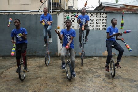 Members of the GKB academy, a unicycle club, juggle while balancing on their unicycles during a training session in Lagos