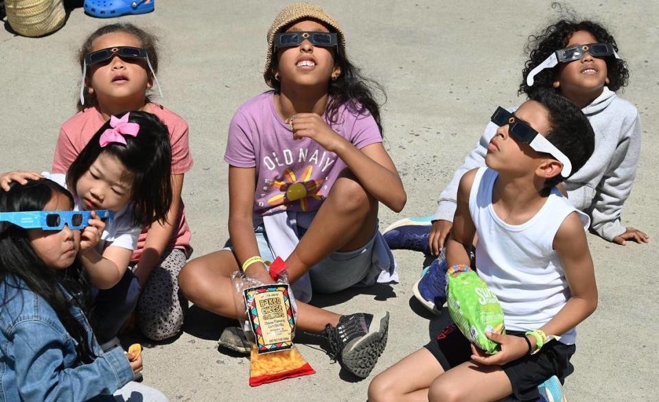 A group of children watch the solar eclipse from the top deck of the Discovery Place parking deck.