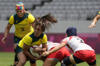 Australia's Evania Pelite looks to pass the baall out under pressure from Japan players, in their women's rugby sevens match at the 2020 Summer Olympics, Thursday, July 29, 2021 in Tokyo, Japan. (AP Photo/Shuji Kajiyama)