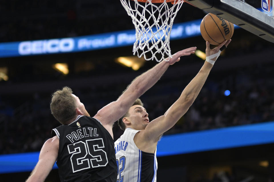 Orlando Magic forward Franz Wagner (22) goes up for a shot in front of San Antonio Spurs center Jakob Poeltl (25) during the first half of an NBA basketball game Friday, Dec. 23, 2022, in Orlando, Fla. (AP Photo/Phelan M. Ebenhack)