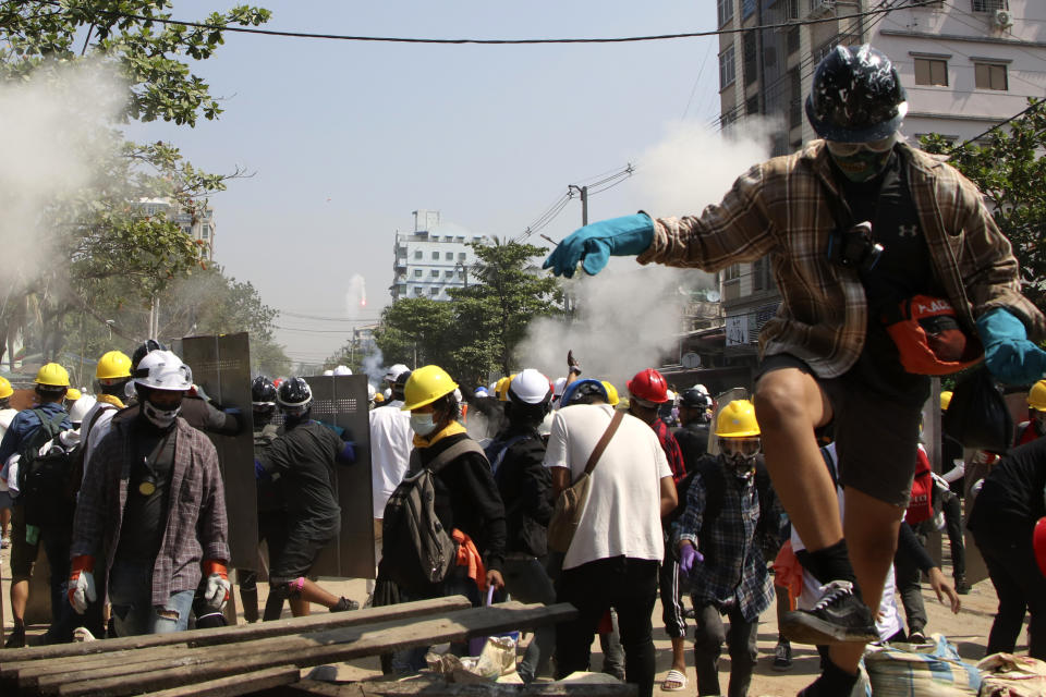 Protesters are dispersed as riot police fired tear gas behind a makeshift barricade in Yangon, Myanmar, Sunday, March 7, 2021. The escalation of violence in Myanmar as authorities crack down on protests against the Feb. 1 coup is raising pressure for more sanctions against the junta, even as countries struggle over how to best sway military leaders inured to global condemnation. (AP Photo)