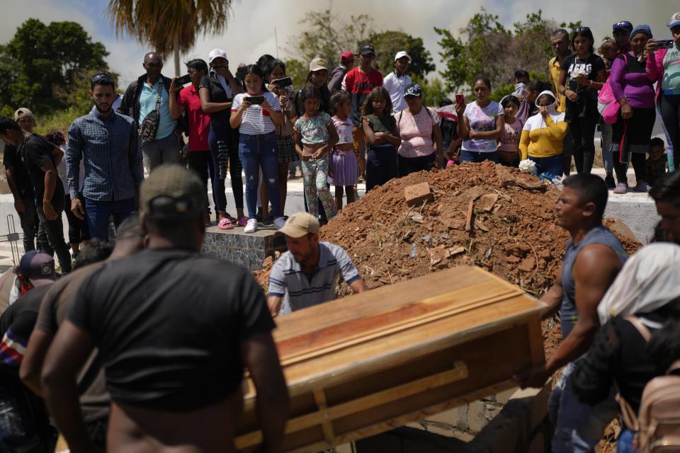 Residents work together to place the coffin that contain the remains of miner Richard Bastardo, into a grave at the cemetery in La Paragua, Bolivar state, Venezuela, Thursday, Feb. 22, 2024. The collapse of an illegally operated open-pit gold mine in central Venezuela killed at least 14 people including Bastardo, and injured several more, state authorities said Wednesday, as some other officials reported an undetermined number of people could be trapped. (AP Photo/Ariana Cubillos)
