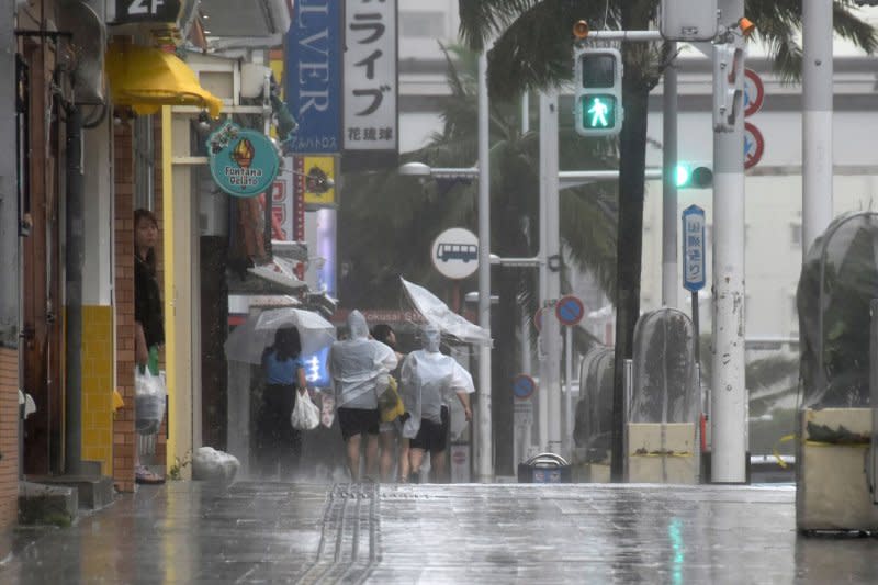 People walk along Kokusai-dori under strong wind and rain by Typhoon Khanun in Naha, Okinawa Prefecture, Japan, on August 2. Typhoon Khanun, which has a central air pressure of 930 hectopascals and a wind velocity of 50 meters per second, forced the cancellation of over 400 flights and the loss of electricity on more than 200,000 houses in the prefecture. Photo courtesy of Jiji Press/EPA-EFE