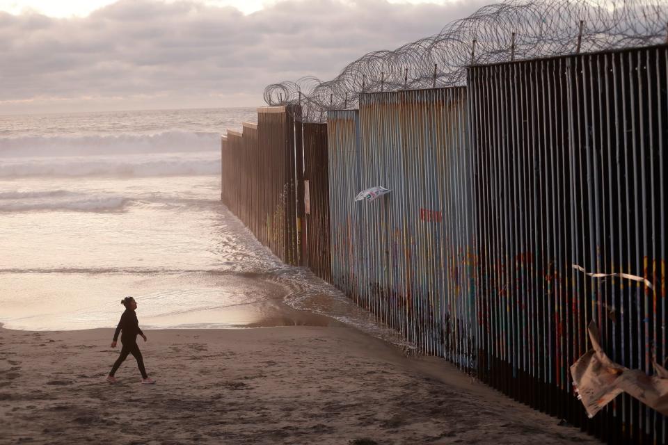 A woman walks on the beach next to a border barrier in Tijuana, Mexico Jan. 9, 2019. President Donald Trump has declared a national emergency to secure billions of dollars to build more barrier along the U.S.-Mexico border and Democrats are trying to halt the declaration.
