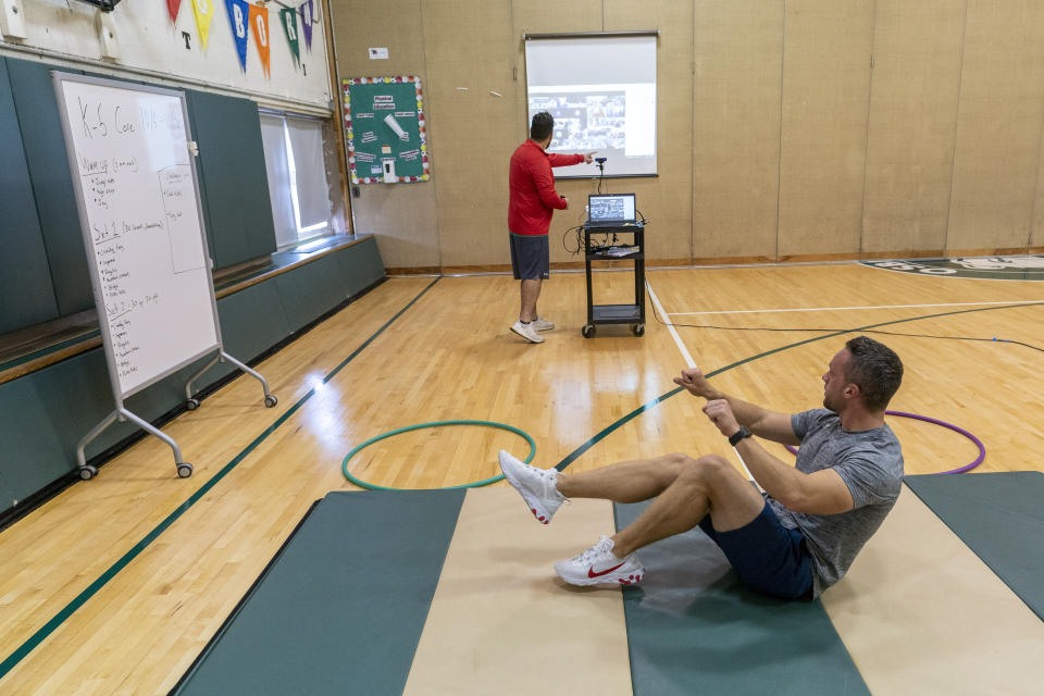 Physical education teachers Jonathan Tuttle, bottom, and Steven Lennon teach a class remotely from the gym at the Osborn School during the coronavirus outbreak, Tuesday, Oct. 6, 2020, in Rye, N.Y. (AP Photo/Mary Altaffer)