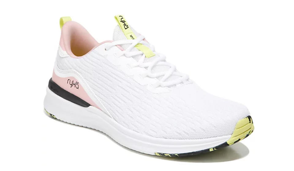 Single white sneaker with blush pink, pale yellow, and black detailing on sole, tongue, and heel