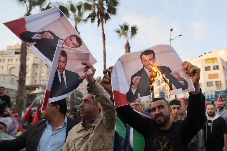 Los palestinos queman carteles del presidente francés Emmanuel Macron, que está de visita en Israel, durante una protesta en la ciudad de Ramallah, en Cisjordania, el 24 de octubre de 2023.