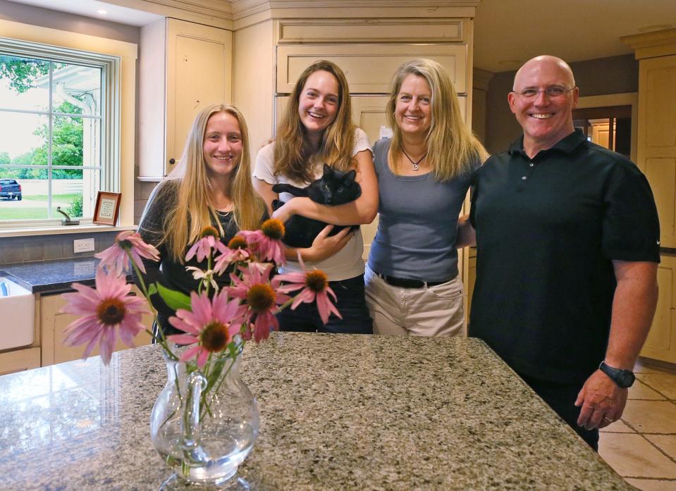 Kristine and Kaitlyn, holding their cat, Monty, pose with their parents, State Sen, Kristina Roegner and their father,Eric, in the kitchen of their home.