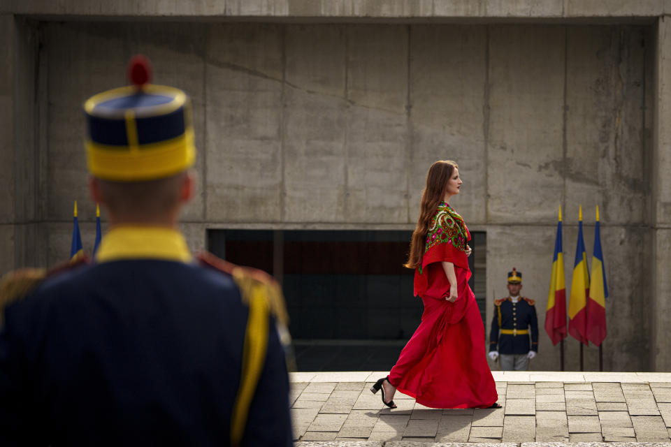 Romanian Roma soprano Isabela Stanescu walks by honor guard soldiers to perform the Romani anthem Gelem, Gelem during a commemoration of the Roma Holocaust Memorial Day, outside the Holocaust memorial, in Bucharest, Romania, Wednesday, Aug. 2, 2023. (AP Photo/Andreea Alexandru)