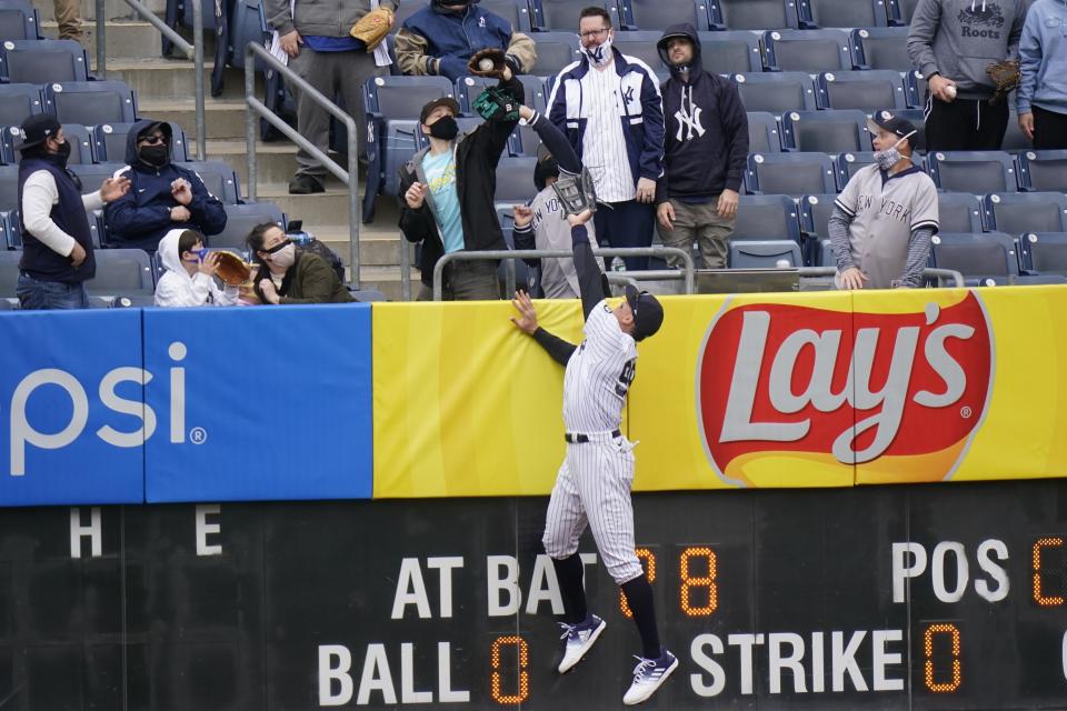 A fan catches a ball hit by Tampa Bay Rays' Francisco Mejia for a home run as New York Yankees right fielder Aaron Judge (99) leaps at the wall during the second inning of a baseball game Saturday, April 17, 2021, in New York.(AP Photo/Frank Franklin II)