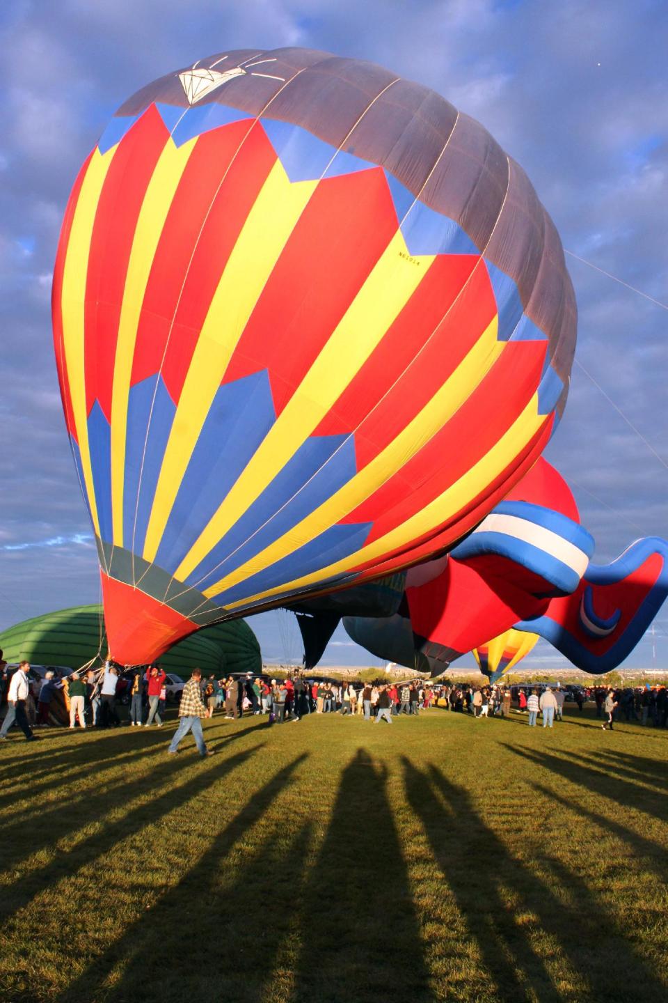 FILE - This Oct. 6, 2011 file photo shows hot air balloons inflating during the 40th annual Albuquerque International Balloon Fiesta in Albuquerque, N.M. There is an entrance fee for the annual fiesta, but the colorful spectacle can be seen from many vantage points around the city once the balloons lift off. (AP Photo/Susan Montoya Bryan, File)