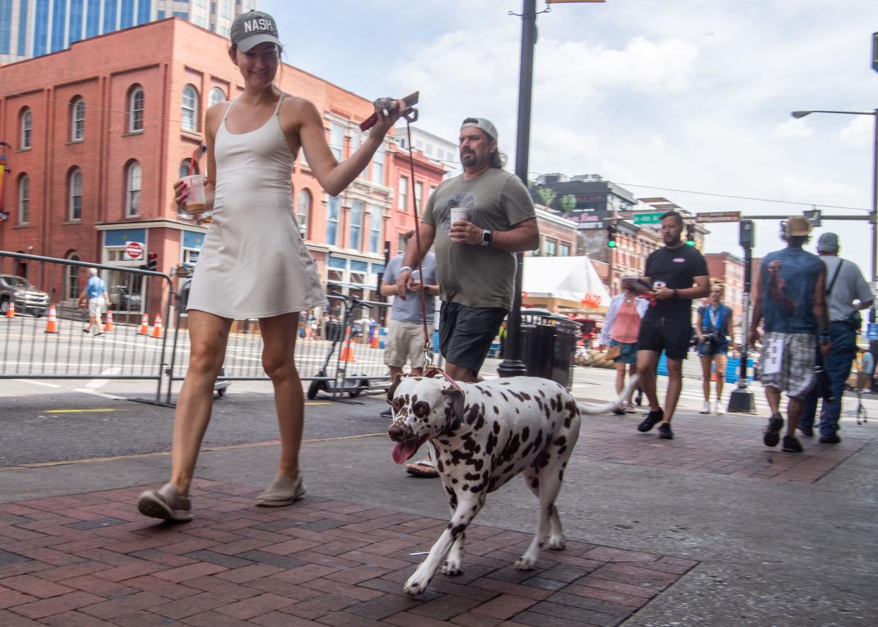 Mary Beth French walks her dog, Piper through downtown at the CMA Fest in Nashville, Tenn., Sunday, June 12, 2022. 