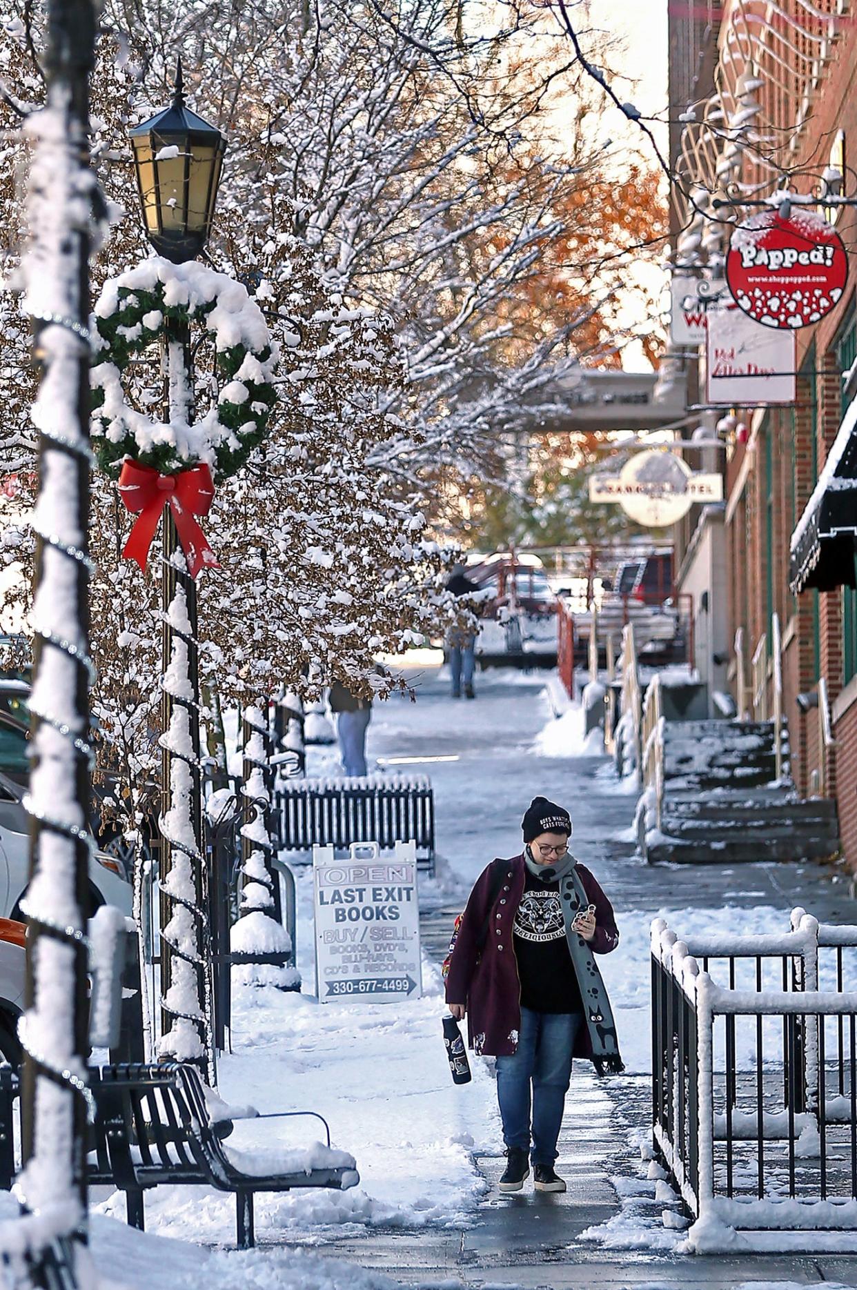 A pedestrian makes their way down a snowy sidewalk on Main Street in Kent on Monday.