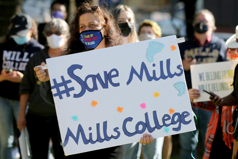 OAKLAND, CA - MARCH 26: Priya Canuga, a San Jose teacher and Mills College graduate from the class of 1993, holds a sign during a rally to demand that the College