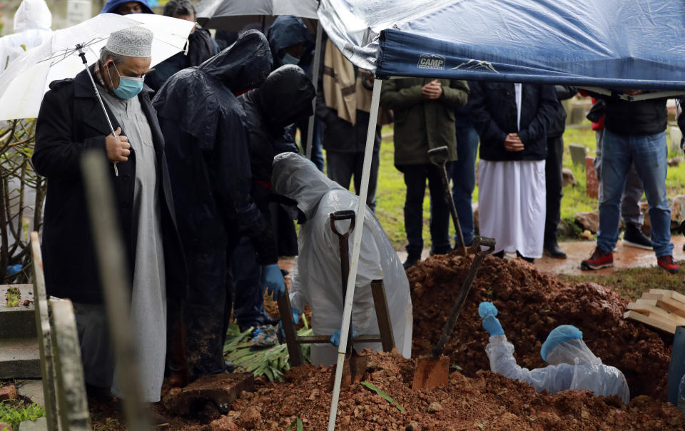 Undertakers wearing personal protective equipment exit the grave of Shaykh Seraj Hassan Hendricks during the funeral at the Mowbray cemetery in Cape Town, South Africa, Friday July 10, 2020. Hendricks who died of COVID-19 was the resident sheikh at the Azzawia Institute. (AP Photo/Nardus Engelbrecht)