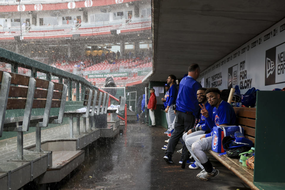 Chicago Cubs' Christopher Morel, right, sits with Jonathan Villar in the dugout as play is suspended due to inclement weather during the sixth inning of a baseball game against the Cincinnati Reds in Cincinnati, Thursday, May 26, 2022. (AP Photo/Aaron Doster)