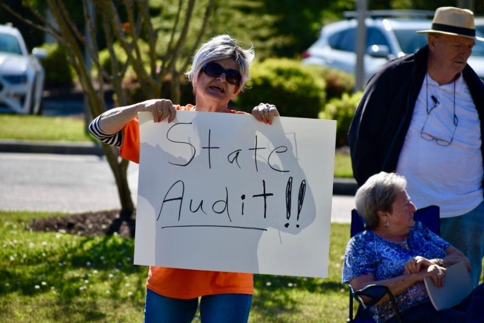 A Leland resident displays a sign demanding a state audit of the town on Saturday, April 13, 2024, at a rally against a proposed property tax increase.