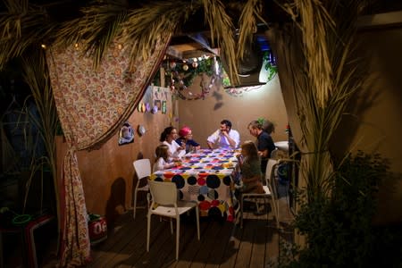 The Stanleigh family sit inside their sukka, or ritual booth, used during the Jewish holiday of Sukkot in their yard, in Jerusalem