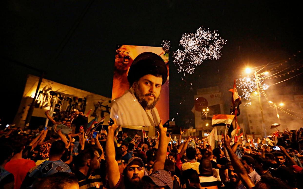 Followers of Shia cleric Moqtada al-Sadr, seen in the poster, celebrate in Tahrir Square, Baghdad, Iraq, early Monday - AP