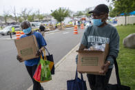 In this Thursday, May 28, 2020, photo, Betty Chandler, left, and Sheila Barron carry groceries they received during a food distribution drive sponsored by Island Harvest Food Bank in Valley Stream, N.Y. The Valley Stream stream donations were just one of many events Island Harvest has conducted throughout the area recently. (AP Photo/Mary Altaffer)
