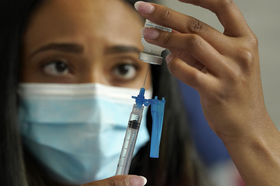 Licensed practical nurse Yokasta Castro, of Warwick, R.I., draws a Moderna COVID-19 vaccine into a syringe at a mass vaccination clinic, Wednesday, May 19, 2021, at Gillette Stadium, in Foxborough, Mass. A month after every adult in the U.S. became eligible for the vaccine, a distinct geographic pattern has emerged: The highest vaccination rates are concentrated in the Northeast, while the lowest ones are mostly in the South. (AP Photo/Steven Senne)