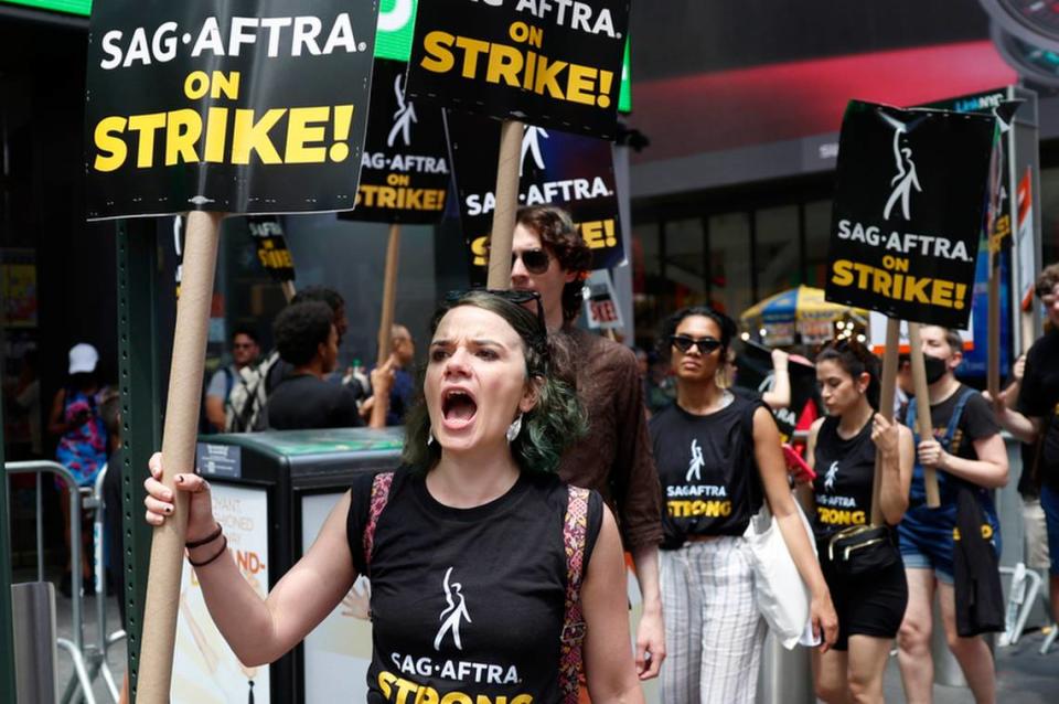 Members of the Writers Guild of America East are joined by SAG-AFTRA members and actors as they both hold up signs picketing in Times Square on July 14, 2023, in New York. SAG-AFTRA representing 160,000 television and movie actors joined screenwriters who were picketing due to a range of issues including pay and the use of artificial intelligence.