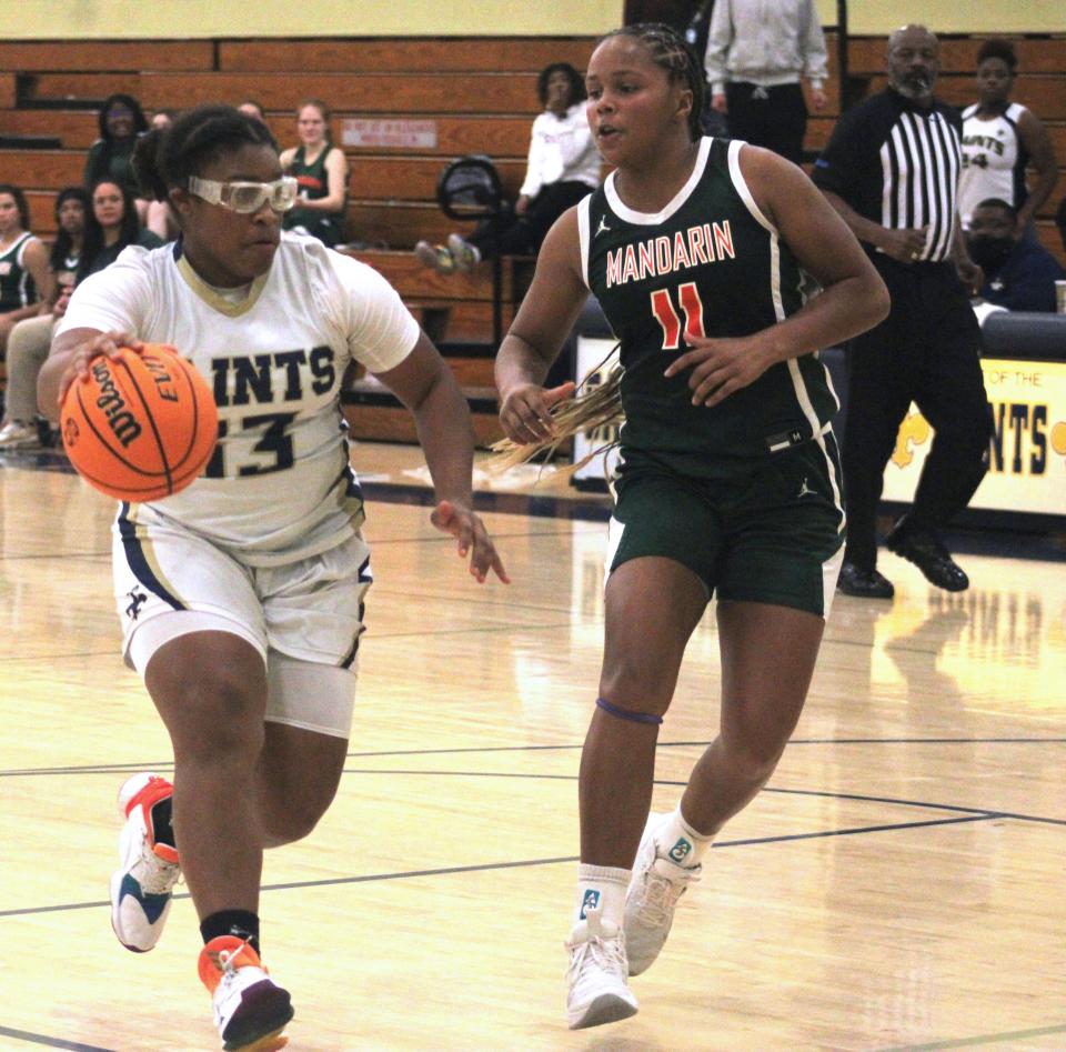 Sandalwood guard Kayla Johnson (33) drives to the basket as Mandarin forward Ellie Jackson (11) defends during a high school girls basketball game on December 1, 2021. [Clayton Freeman/Florida Times-Union]