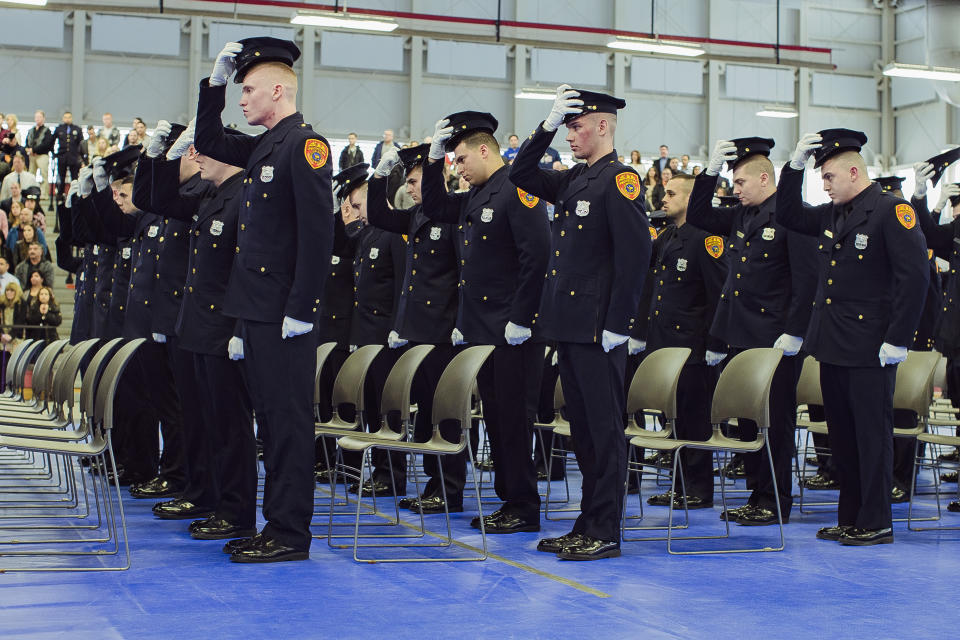 Matias Ferreira, second row, second, and his colleagues take off his hat during their graduation from the Suffolk County Police Department Academy at the Health, Sports and Education Center in Suffolk, N.Y., Friday, March 24, 2017. Ferreira, a former U.S. Marine Corps lance corporal who lost his legs below the knee when he stepped on a hidden explosive in Afghanistan in 2011, is joining a suburban New York police department. The 28-year-old graduated Friday from the Suffolk County Police Academy on Long Island following 29 weeks of training. (AP Photo/Andres Kudacki)