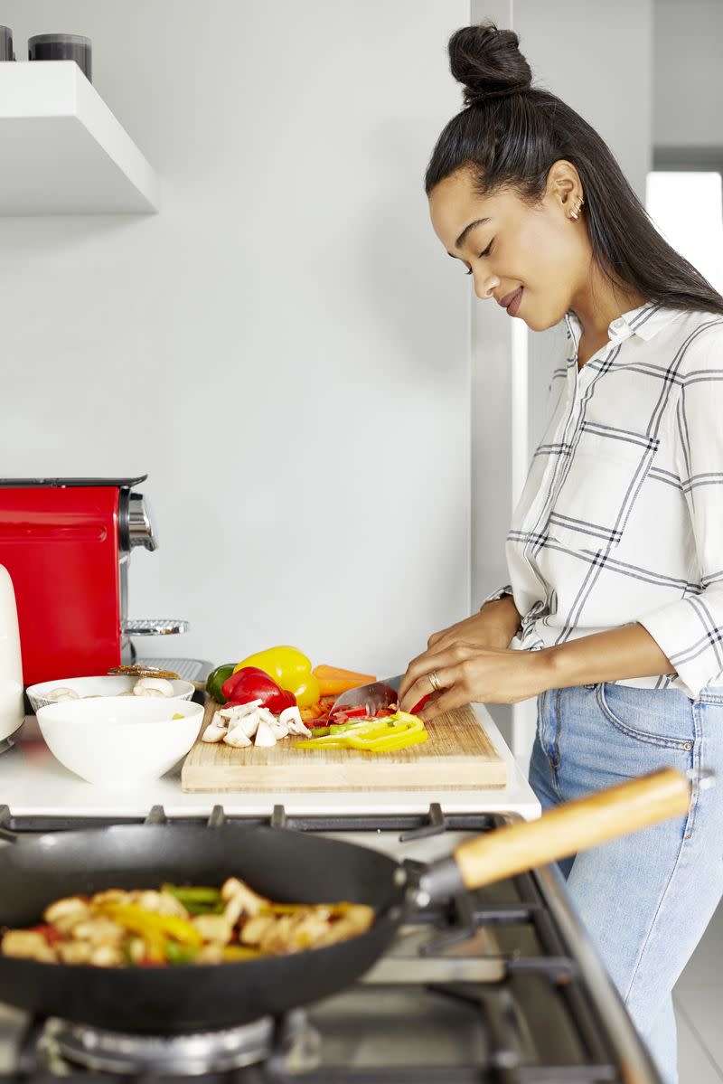 A woman chopping vegetables at a kitchen counter