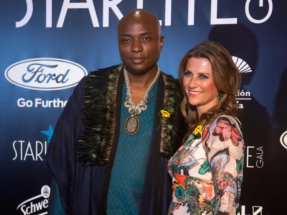 Shaman Durek wears a teal patterned shirt under a navy jacket next to Princess Märtha Louise of Norway in a printed pink dress