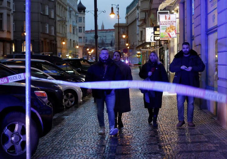 Unos transeúntes caminan cerca del parea acordonada por la policía checa tras un tiroteo en el que murieron al menos 15 personas en una universidad de Praga. Diciembre 21, 2023. REUTERS/David W Cerny