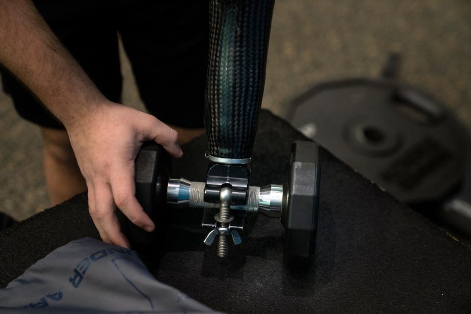 Manna prepares to use dumbbells at the Wayne YMCA. His prosthesis has attachments designed for different weightlifting equipment.