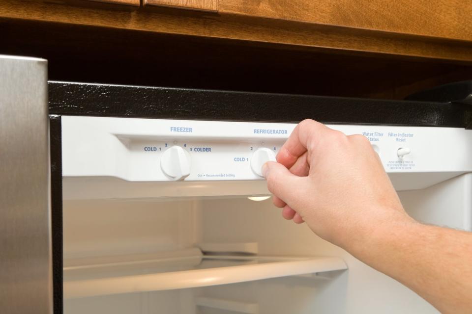 Person adjusting a refrigerator's temperature