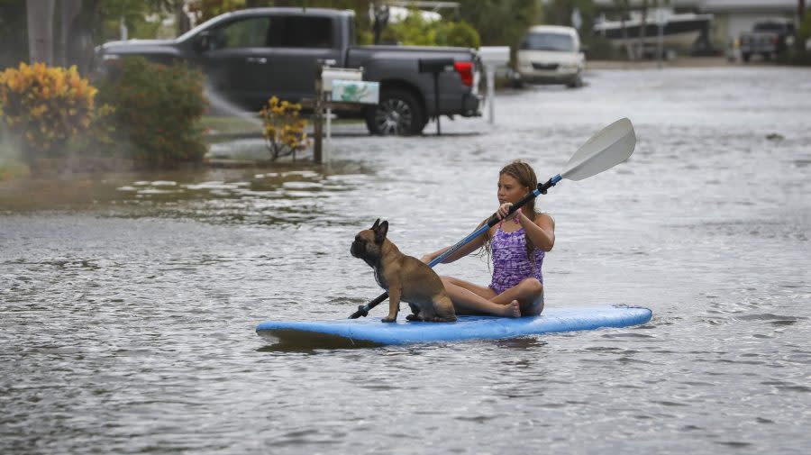 Lily Gumos, 11, of St. Pete Beach, kayaks with her French bulldog along Blind Pass Road and 86th Avenue Wednesday, Aug. 30, 2023 in St. Pete Beach, Fla. Hurricane Idalia made landfall Wednesday in Florida as a Category 3 storm and unleashed devastation along a wide stretch of the Gulf Coast, submerging homes and vehicles, turning streets into rivers, unmooring small boats and downing power lines in an area that has never before received such a pummeling. (Chris Urso/Tampa Bay Times via AP)