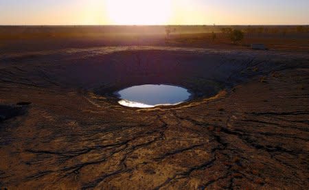 A truck stirs up dust on a road behind a dam on farmer May McKeown's drought-affected property located on the outskirts of the northwestern New South Wales town of Walgett in Australia, July 19, 2018. REUTERS/David Gray/Files