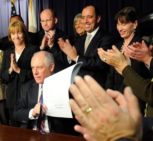 Then-Gov. Pat Quinn is applauded as he displays the state's firstcampaign finance bill signed into law that imposes limits on candidates, political parties and political action committees on Dec. 9, 2009, in Chicago. The reforms were inspired by the scandal surrounding former Gov. Rod Blagojevich who was arrested on federal corruption charges and later removed from office by lawmakers. (AP Photo/Chicago Sun-Times, John H. White)