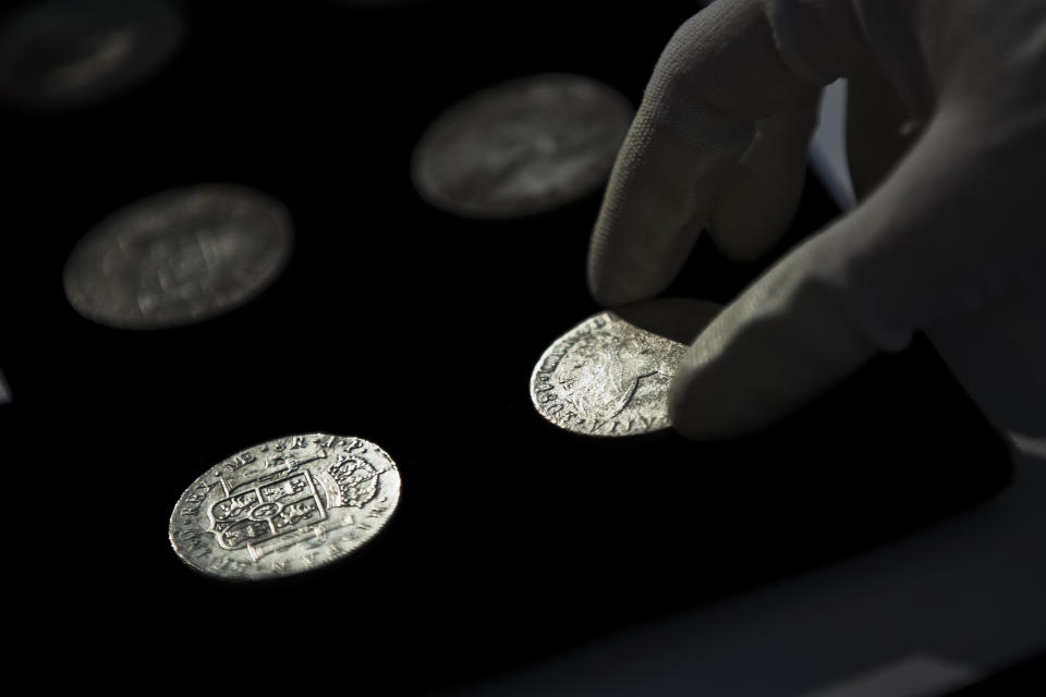 A worker of the ministry places silver coins from the shipwreck of a 1804 galleon, on its first display to the media at a ministry building, in Madrid, Friday, Nov. 30, 2012. Spanish cultural officials have allowed the first peep at 16 tons (14.5 metric tons) of the shipwreck, 'Nuestra Senora de las Mercedes' a treasure worth an estimated $500 million that a U.S. salvage company gave up after a five-year international ownership dispute. (AP Photo/Daniel Ochoa de Olza)