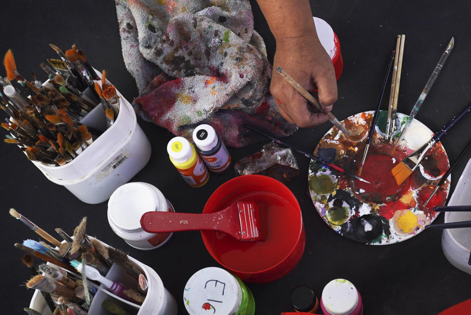 Artist Adriana Aldaraca prepares her paints to craft a devil-like cardboard figure popularly known as "Judas," for the upcoming "Burning of Judas," celebration, at the Santa Maria La Ribera Cultural Center in Mexico City, Wednesday, April 5, 2023. Originally, the burning figures were effigies of Judas Iscariot, the apostle who betrayed Jesus, according to the Biblical account of the days leading up to Christ's crucifixion. Nowadays, Mexican artisans shape their Judas like red, horned devils or other characters considered evil. (AP Photo/Marco Ugarte)