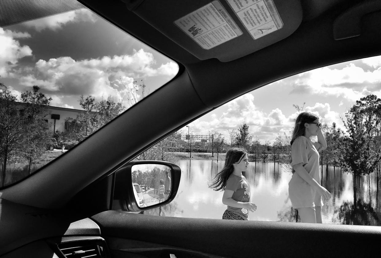 A mother and her daughter walk back to their car while waiting in a line that extended miles at one of the few gas stations open after Hurricane Irma in Fort Myers, Fla. (Photo: Holly Bailey/Yahoo News)