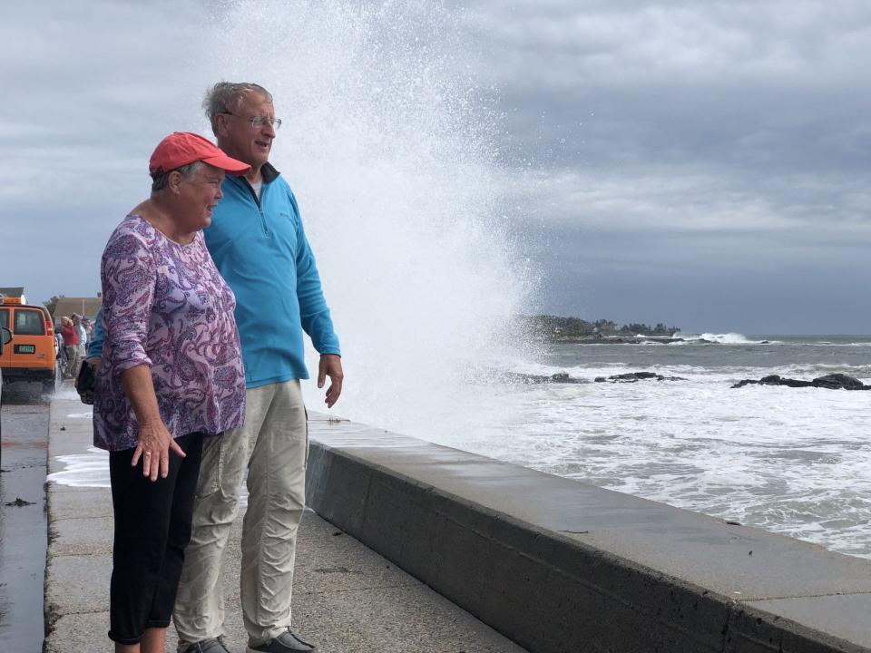 Kim and Rich Pelczar, of Connecticut, are spared a wave that crashes against the seawall behind them as they watch the effects of Hurricane Lee rile up the Atlantic Ocean in Kennebunk, Maine, on Saturday, Sept. 16, 2023.