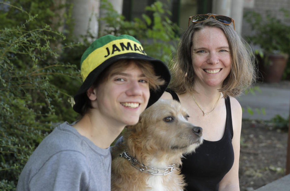 Jennifer Haller, right, the first person to receive a trial dose of a COVID-19 vaccine, poses for a photo with her son Hayden, 16, and their dog Meg, Sunday, July 19, 2020, in Seattle. As the world's biggest COVID-19 vaccine study gets underway more than four months after Haller and 44 others became the first participants in a phase-one coronavirus vaccine study that has produced encouraging results, Haller is encouraging other people to sign up for future trials. (AP Photo/Ted S. Warren)