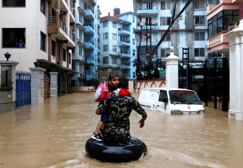 FILE PHOTO: A member of Nepalese army carrying a child walks along the flooded colony in Kathmandu