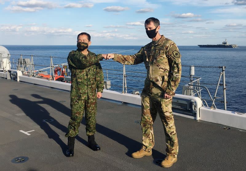 Lieutenant General Kevin Schneider, commander of U.S. Forces Japan, and General Koji Yamazaki, Japan's top military commander of Chief of Staff of Joint Staff greet each other on the destroyer JS Kaga at mid-sea off south of Japan