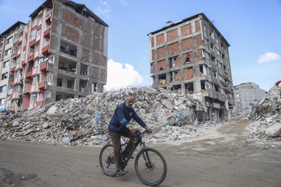 A man rides a bicycle past destroyed buildings in Antakya, southeastern Turkey, Tuesday, Feb. 21, 2023. The death toll in Turkey and Syria rose to eight in a new and powerful earthquake that struck two weeks after a devastating temblor killed nearly 45,000 people, authorities and media said Tuesday. (AP Photo/Unal Cam)